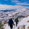 a couple of people walking up a snow covered slope