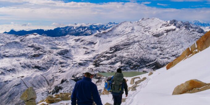 a couple of people walking up a snow covered slope