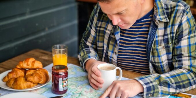 a man sitting at a table with a plate of food and a cup of coffee