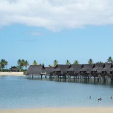 a row of huts sitting on top of a beach next to a body of water