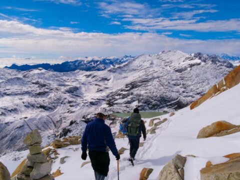 a couple of people walking up a snow covered slope